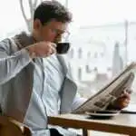Un homme en train de lire son journal pendant qu'il boit le café