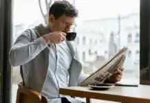 Un homme en train de lire son journal pendant qu'il boit le café